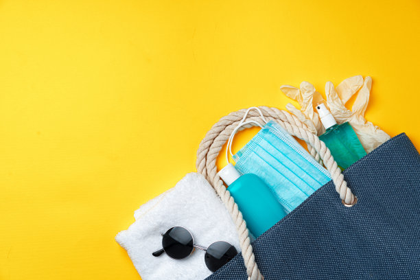 蓝色沙滩包与沙滩配件和保护面具在黄色的背景图片下载