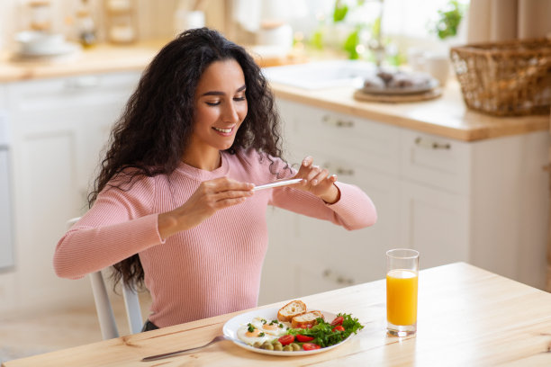 美食博客。微笑的年轻女子正在用智能手机拍早餐图片下载