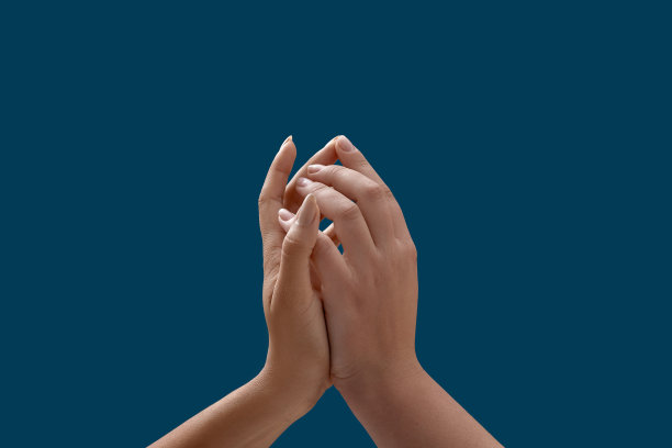 特写的两个女性的手互相接触，团结孤立的蓝色背景图片下载