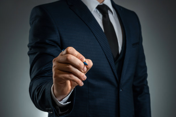 一个穿着西装的男人拿着一支圆珠笔在空中写字。股票的经营理念。特写,复制空间。图片下载