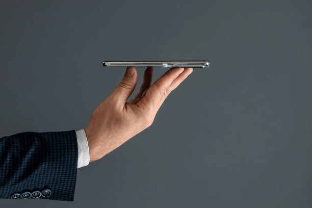 一个穿着西装的商人的手拿着智能手机的水平侧视图。特写镜头。图片下载