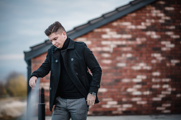 一个英俊的年轻商人穿着休闲的造型，站在一个办公大楼的阳台上，摆姿势并为他的网站拍摄一组照片。图片下载