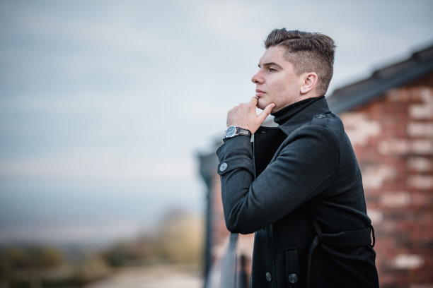 一个英俊的年轻商人穿着休闲的造型，站在一个办公大楼的阳台上，摆姿势并为他的网站拍摄一组照片。图片下载