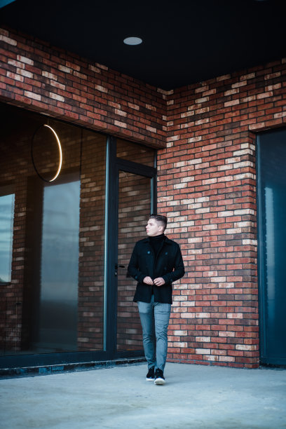 一个英俊的年轻商人穿着休闲的造型，站在一个办公大楼的阳台上，摆姿势并为他的网站拍摄一组照片。图片下载