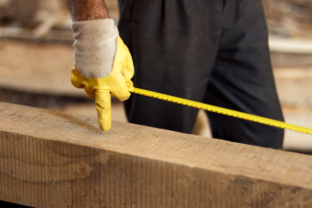 一个戴着工作手套的男人拿着卷尺。图片下载