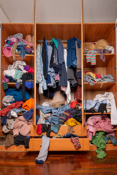 巨大的衣橱里堆满了旧衣服，胡乱地从架子和衣架上往下推挂着。衣柜混乱图片下载