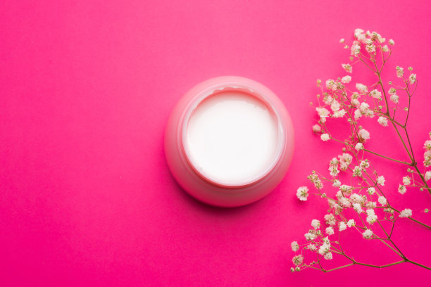 花里的面霜。粉色背景上的面霜。皮肤护理。美容业。副本的空间。白色的花朵。关于正确选择奶油的文章。奶油的选择。水疗。图片下载