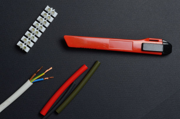 刀，剥线与端子排和热收缩管躺在黑暗的背景。从以上观点。图片下载