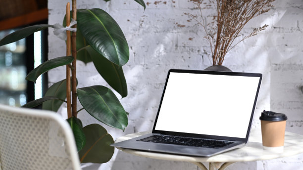 在最小的咖啡馆里，白色的桌子上放着空白屏幕的模拟笔记本电脑。图片下载