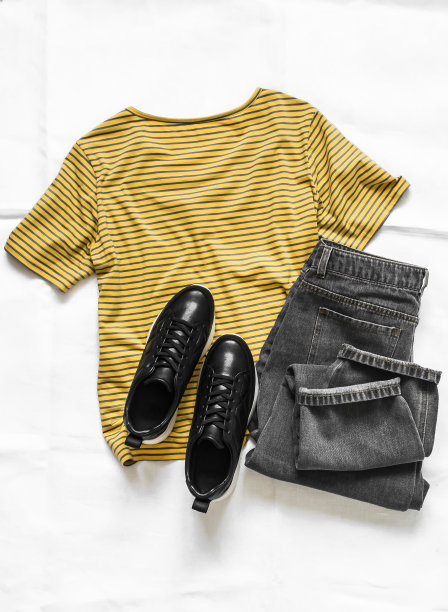 女士的衣服-黄色棉条纹t恤，灰色妈妈牛仔裤和黑色皮革运动鞋在一个浅的背景，俯视图图片下载