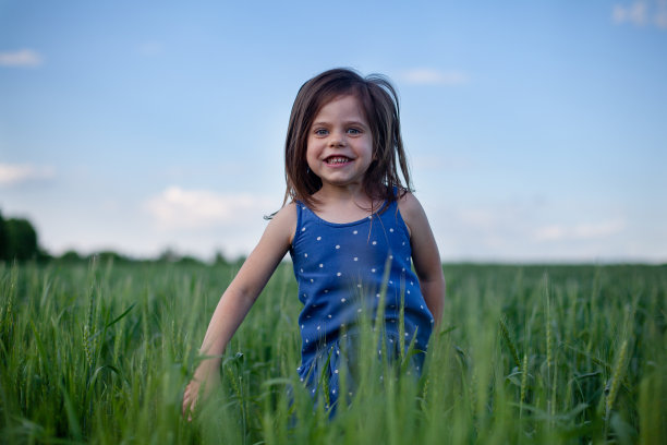 快乐的姑娘走在绿色的麦田里，享受着田野里的生活。大自然的美丽，蓝天和麦田。自由的概念图片下载