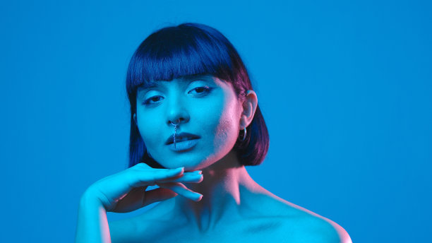 年轻女子触摸她的脸孤立在蓝色霓虹灯copyspace图片下载