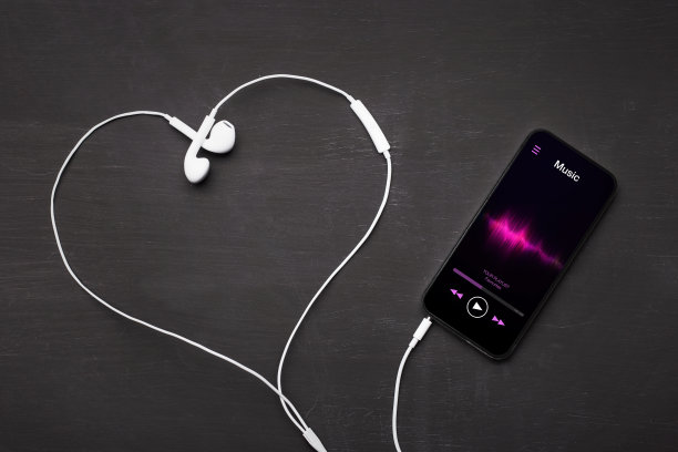 手机与音乐播放器应用程序打开和耳机塑造爱心象征。图片下载