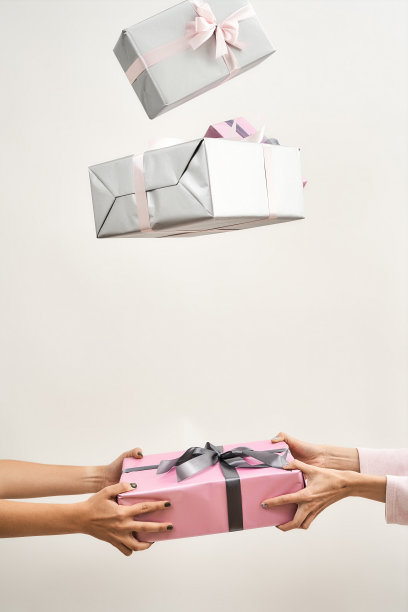 两名妇女在灯光背景下抛起彩色礼盒的剪影图片下载