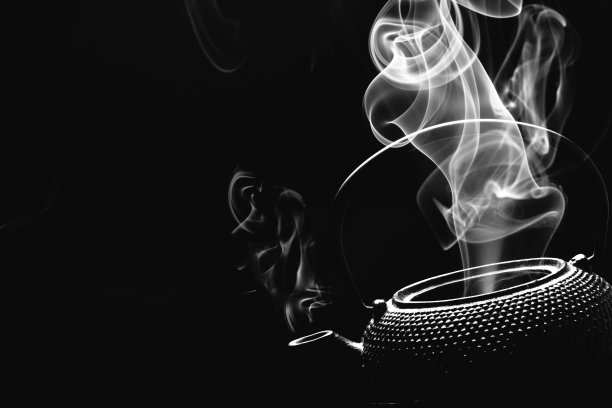 古董茶壶与热气腾腾的茶在黑色的背景。图片下载