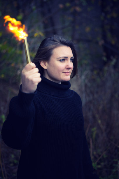 在黑暗中拿着手电筒的黑发女人的肖像图片下载