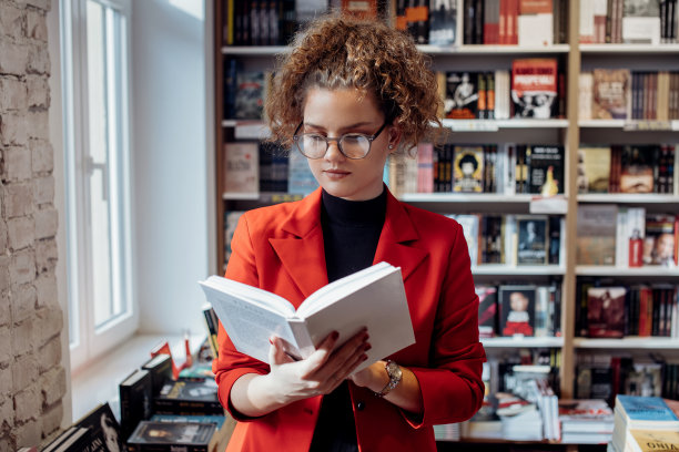 年轻女子正在读书。年轻的女学生正在书店看书。图片下载