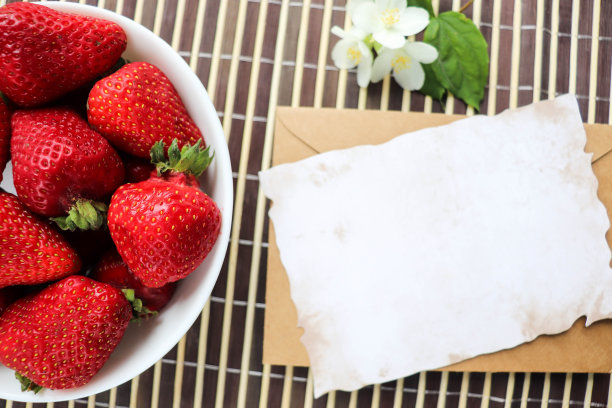 白色盘子上放着成熟的新鲜草莓和茉莉花图片下载