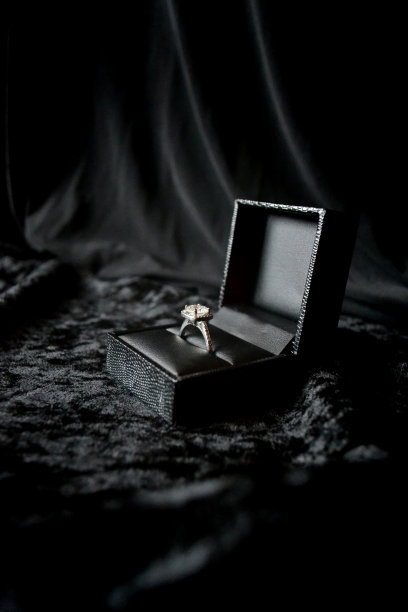 黑色背景衬托下的戒指盒里的银色戒指图片下载