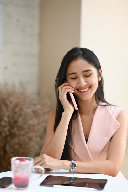 快乐的女商人坐在现代咖啡馆里打手机。图片下载