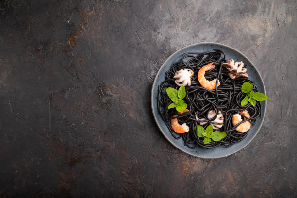 黑色墨鱼意大利面，虾或对虾和小章鱼在黑色混凝土背景。俯视图，平放，复制空间。图片下载