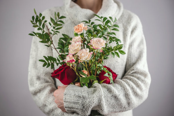 一位身穿毛衣的女人手捧一束娇嫩的鲜花，春意盎然，浪漫温馨图片下载