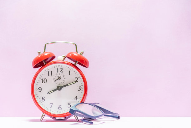 粉色背景上的模拟时钟和眼镜图片下载