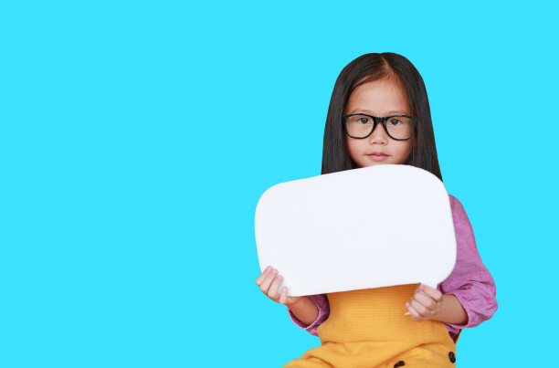 亚洲的小女孩抱着一个空的空白讲话气泡说一些东西与直视相机孤立在青色的背景。教育与会话概念图片下载