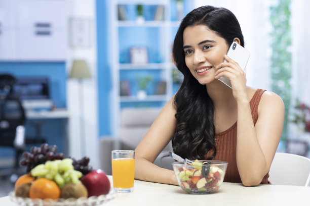 女人的肖像吃水果沙拉，并在电话股票照片交谈图片下载