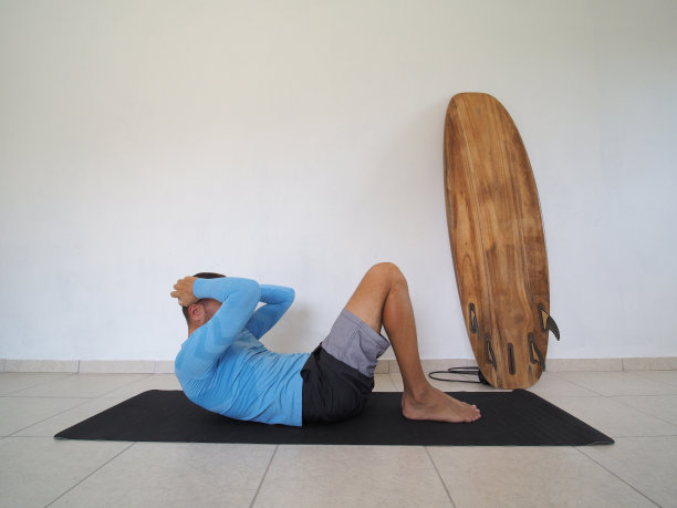 健身房在家里。男人躺在家里的地毯上做腹部运动。图片下载