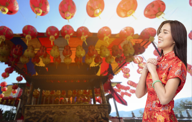 春节快乐女人穿红色旗袍。亚洲华人妇女红衣手祈祷愿好运财运，幸福美满。中国女孩笑脸在唐人街庆祝中国新年图片下载