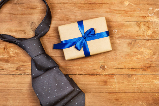 木桌上放着一条灰色领带和一份礼物图片下载