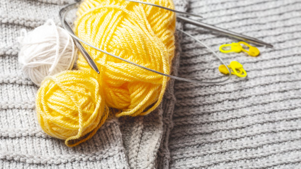 对针织配件。黄色和灰色的纱线，编织针图片下载