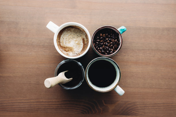 多重咖啡杯，牛奶，豆子和磨碎的咖啡在罐子里的木制背景图片下载
