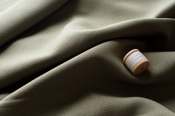 抽象的背景，弯曲的黑色美丽的织物和线轴与白色的线，复制空间。缝纫极简主义的概念。披着的灰色织物躺在美丽的波浪中图片下载