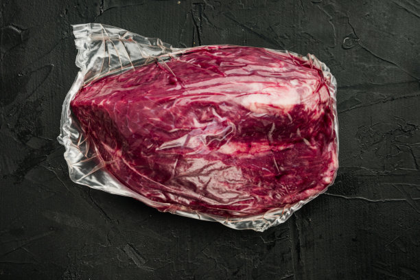 真空包装有机生牛肉，在黑色背景，俯视图平lay图片下载