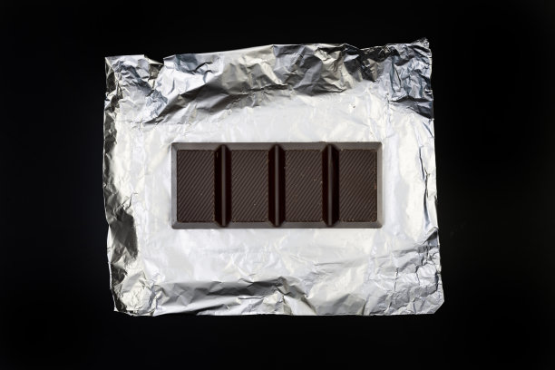 甜美可口的巧克力棒上的银箔上的黑色背景图片下载