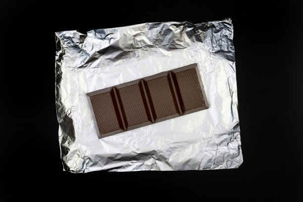 甜美可口的巧克力棒上的银箔上的黑色背景图片下载