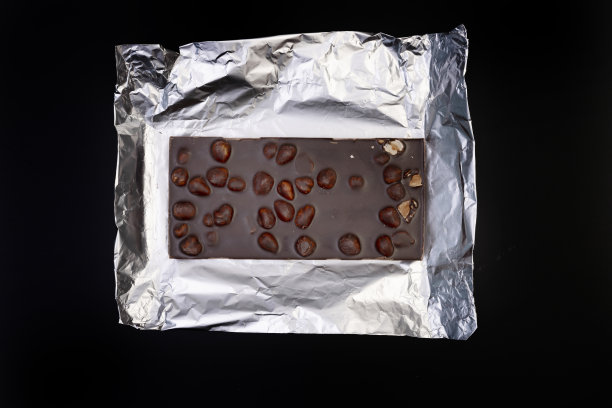 甜美可口的巧克力棒上的银箔上的黑色背景图片下载