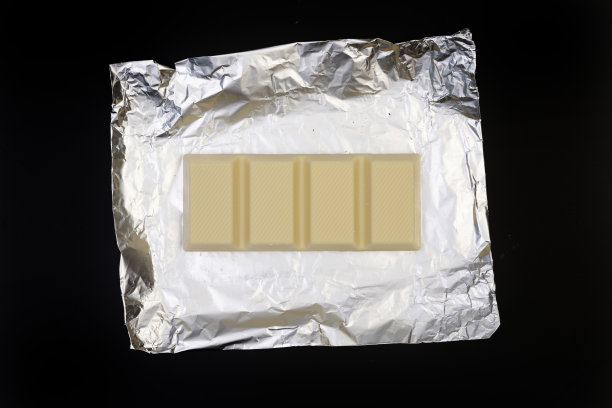 甜美可口的巧克力棒上的银箔上的黑色背景图片下载