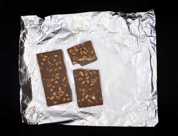 甜美可口的巧克力棒上的银箔上的黑色背景图片下载