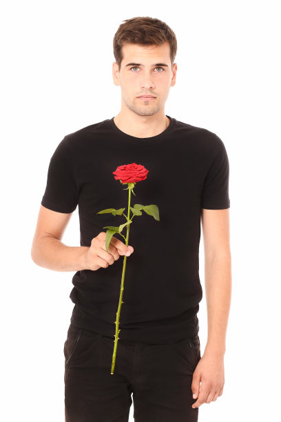情人节和母亲节。英俊的男子站在一个红玫瑰在黑衣服孤立在白色的背景图片下载