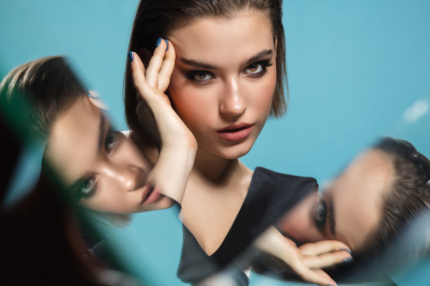 肖像的女性时装模特与反射镜周围她的脸。风格和美学理念。关闭了。图片下载