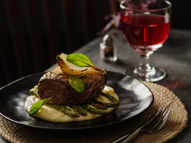 牛排配土豆泥和芦笋在一个黑色盘子里。餐厅晚餐图片下载