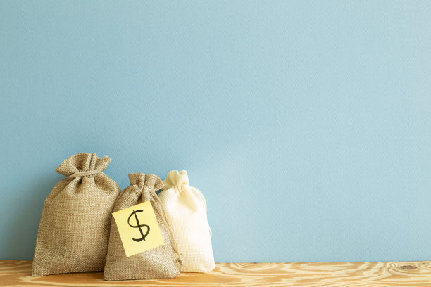 木桌上放着钱袋。蓝色背景图片下载