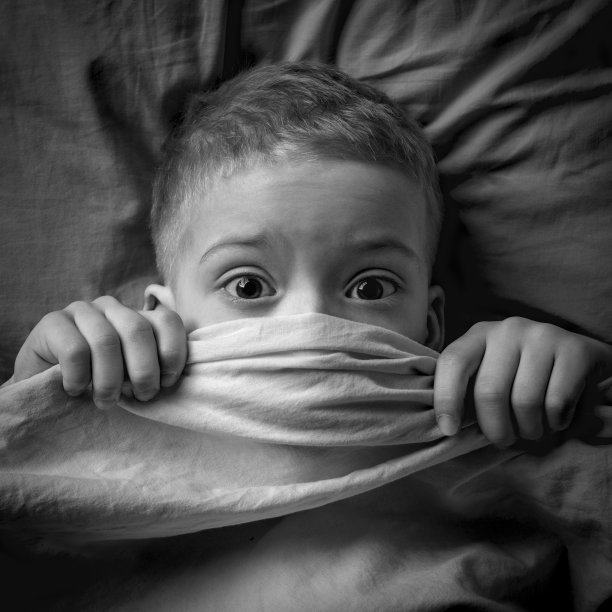 一个睁着眼睛躺在床上的孩子的黑白肖像。这孩子害怕妖怪图片下载