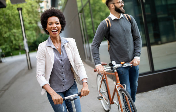快乐的商务人士上班骑自行车，电动踏板车在城市街道上图片下载