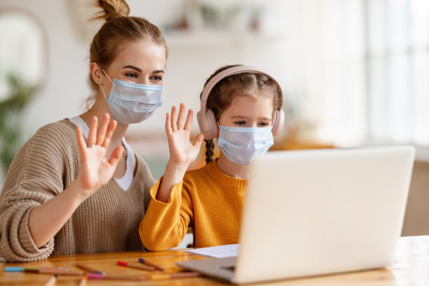 在大流行期间，母亲帮助女儿进行远程教育，并在在线课堂上问候老师图片下载