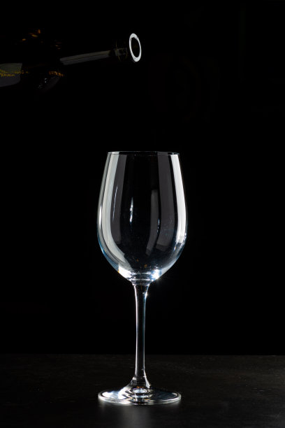 红酒倒入杯中，在黑色的背景上滴着酒图片下载