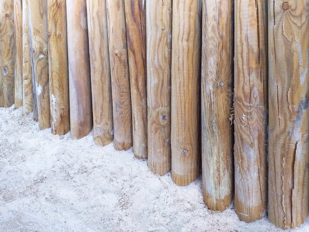 白沙上的圆形木桩透视图。在法属西印度群岛用竹竿做成的篱笆的特写。建筑和建筑概念。图片下载